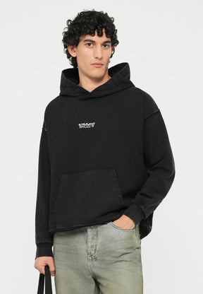 Black hooded sweatshirt with front pocket, light green jeans, white sneakers, and a black bag. Casual fit with a soft texture.