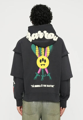 Felpa nera con grafica colorata che presenta un sorriso giallo e foglie. Abbinata a jeans larghi verde oliva e sneaker bianche.