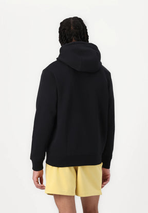 Felpa nera con cappuccio dal taglio ampio, polsini e orlo a coste, abbinata a pantaloni corti giallo chiaro. Il tessuto sembra morbido e liscio.