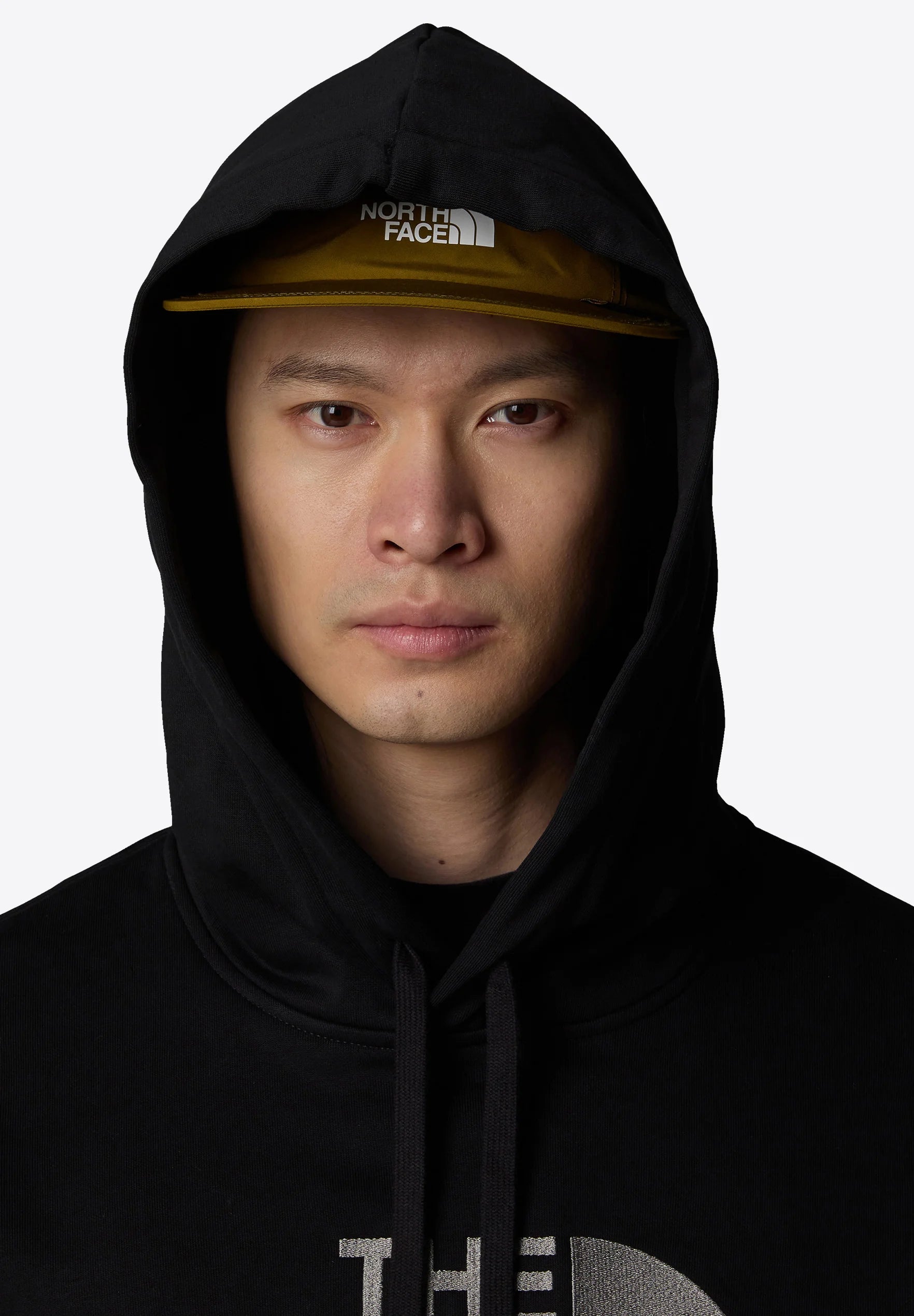 Felpa nera con cappuccio e grande logo, dotata di cappuccio con stringa di regolazione e berretto con visiera gialla a contrasto, che mette in evidenza la texture e il colore del tessuto.