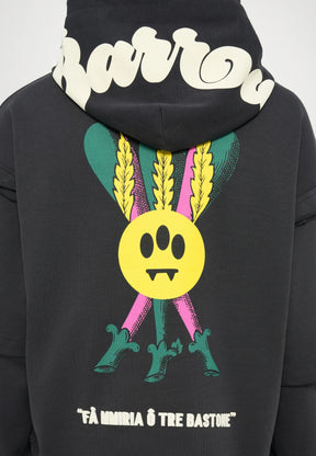 Felpa nera con cappuccio che presenta una grande grafica colorata sul retro: un cerchio giallo con tre occhi, affiancato da piume verdi e accenti rosa.